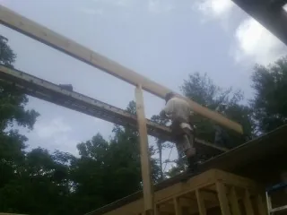 Carpenter setting a ridge beam over a new addition frame — Ice Dam Removal by Roofing Brothers in Fruitport