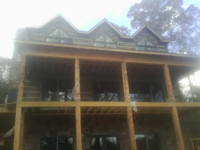 Dormers and porch framing on a large log home under construction — Roof Coating work by our crew in Fruitport