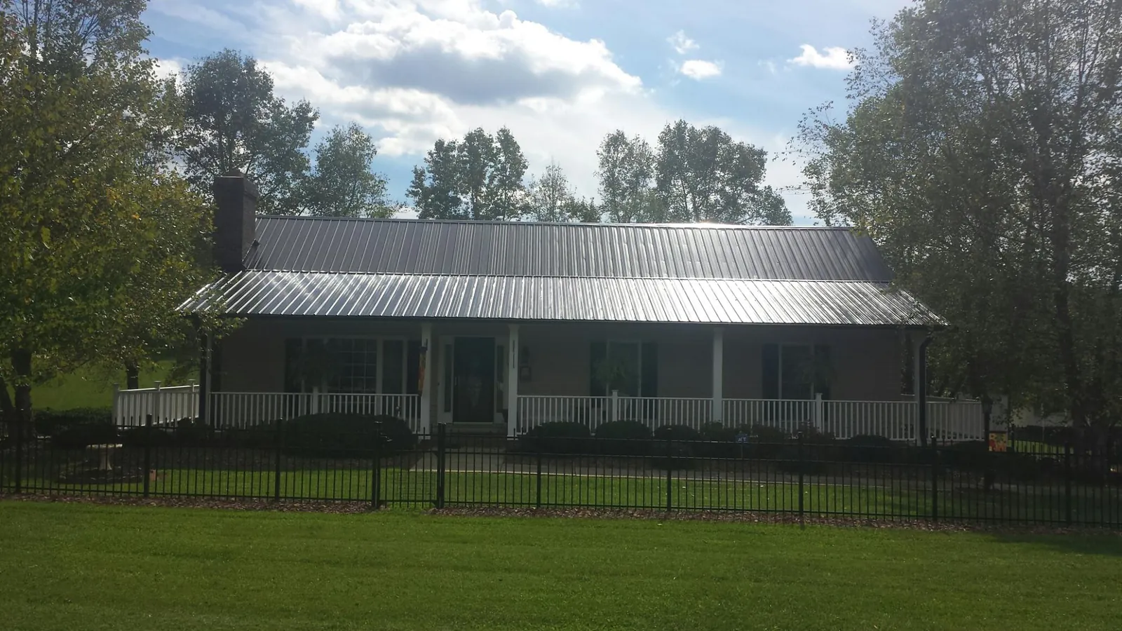 Gray metal roof on a brick ranch with a full width front porch — Gutter Guard Installation work by our crew in Fruitport