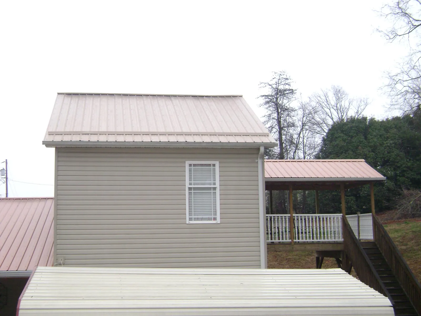 Tan metal roofs on a two story addition and attached porch, from a Roof Replacement job in Fruitport