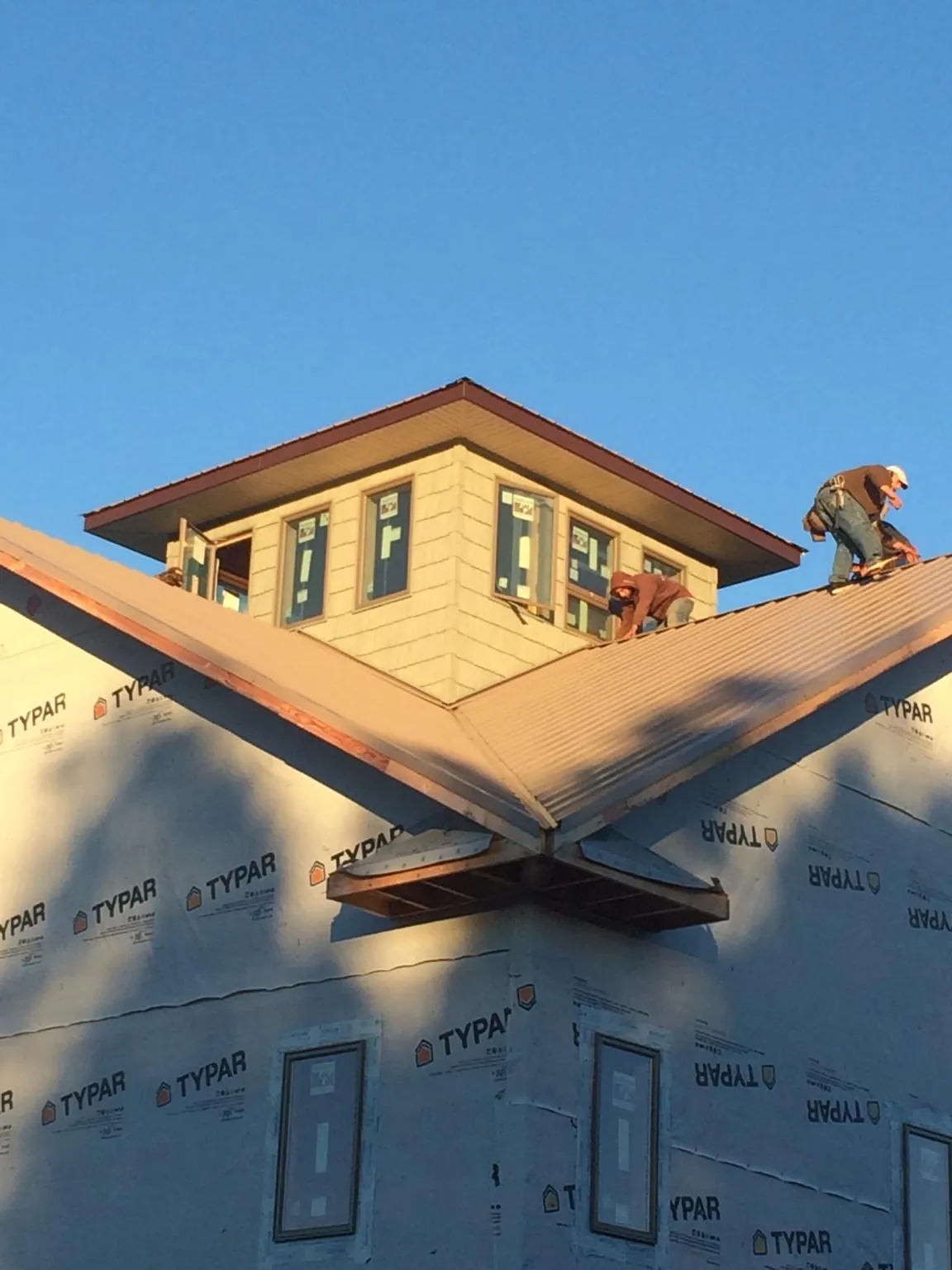 Roofers working around a rooftop cupola on a new metal roof at sunset — Roof Waterproofing in Fruitport by Roofing Brothers